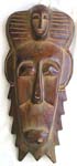 Long brown wooden mask with face decor on top and spiky around face